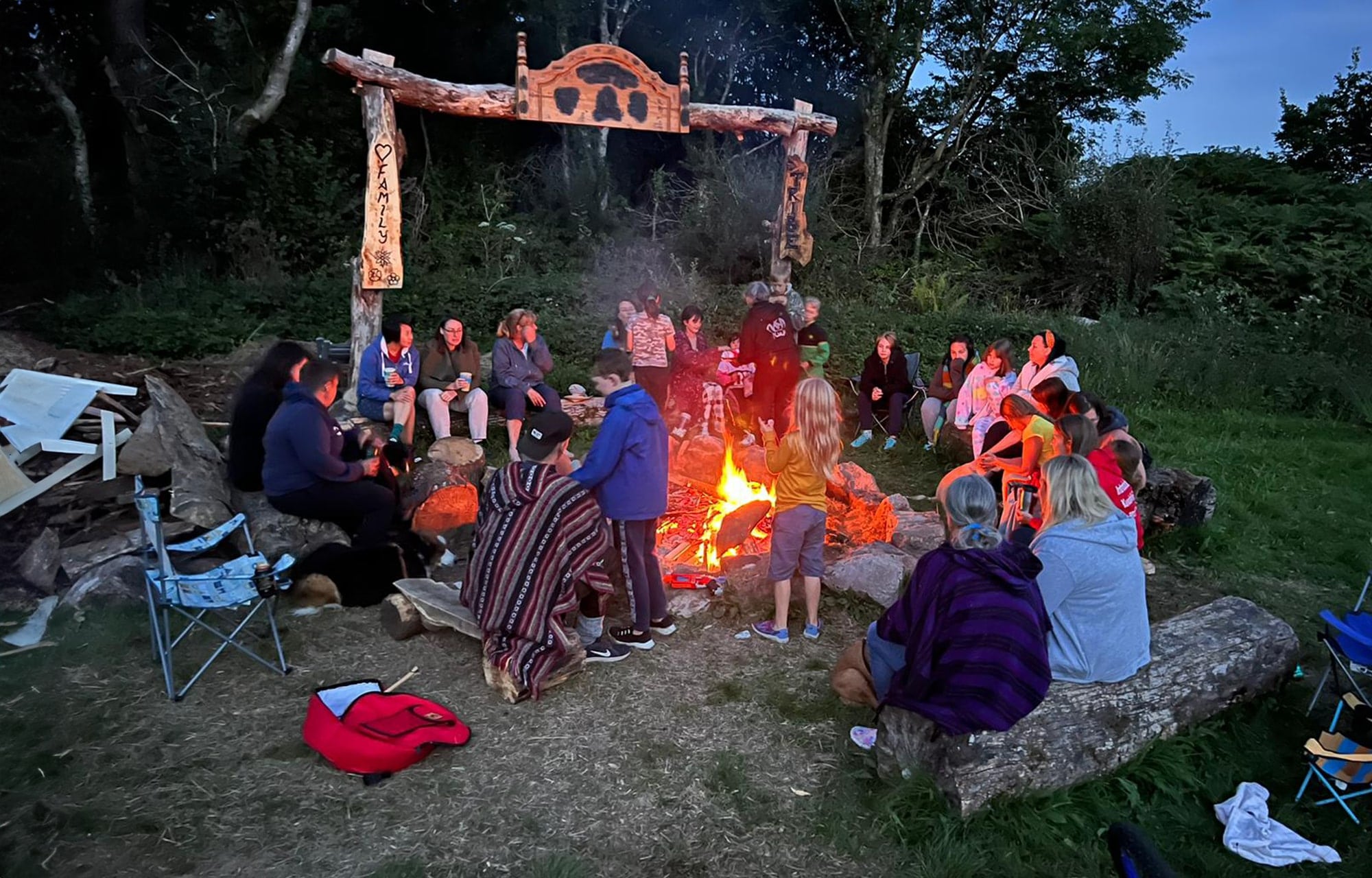 people sitting a round a campfire together in the evening